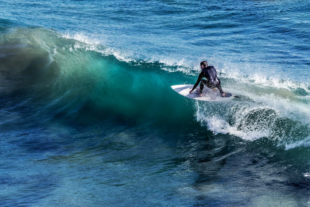 A surfer riding across the face of a blue wave